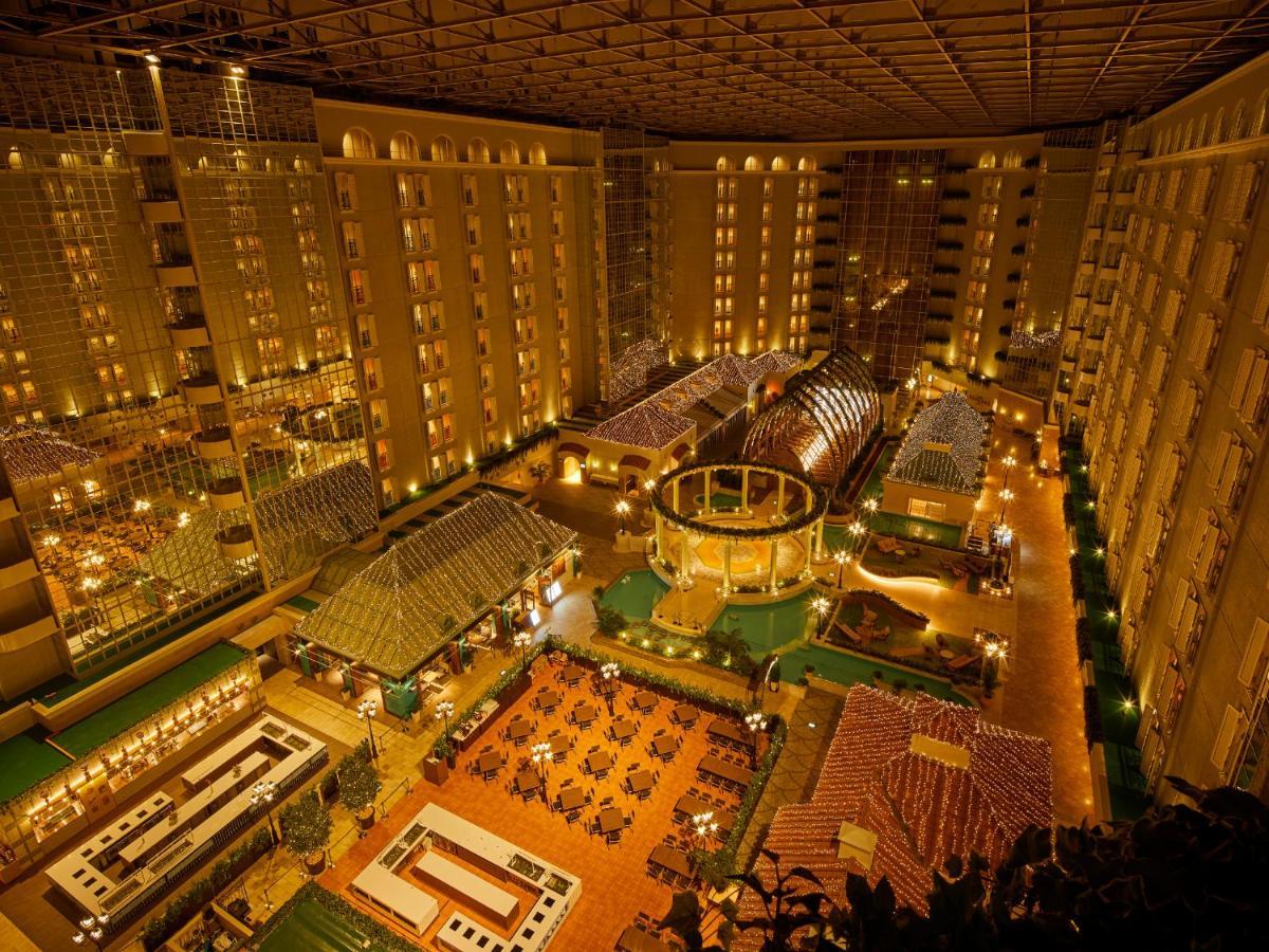 Grand Nikko Tokyo Bay Maihama Hotel Urayasu Eksteriør billede The photo shows a large, illuminated atrium of a hotel or resort complex. Several floors of what appear to be guest rooms or apartments surround the central area. The atrium contains a variety of amenities, including a pool or water feature, landscap
