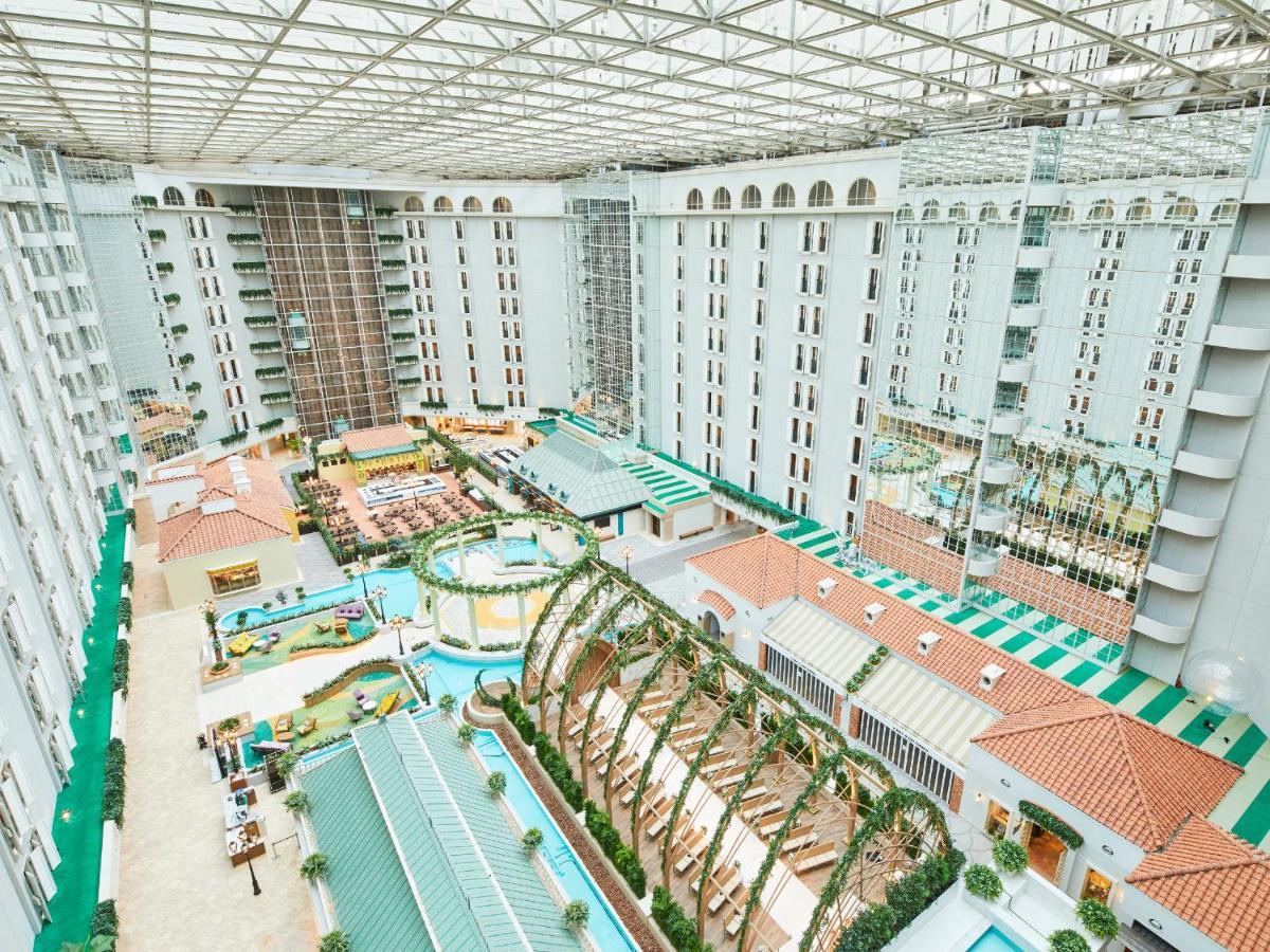 Grand Nikko Tokyo Bay Maihama Hotel Urayasu Eksteriør billede The photo shows a large indoor space, likely a hotel or resort atrium. The area features multiple levels of buildings surrounding a central courtyard. This courtyard includes various amenities such as pools, landscaped gardens, and recreational areas