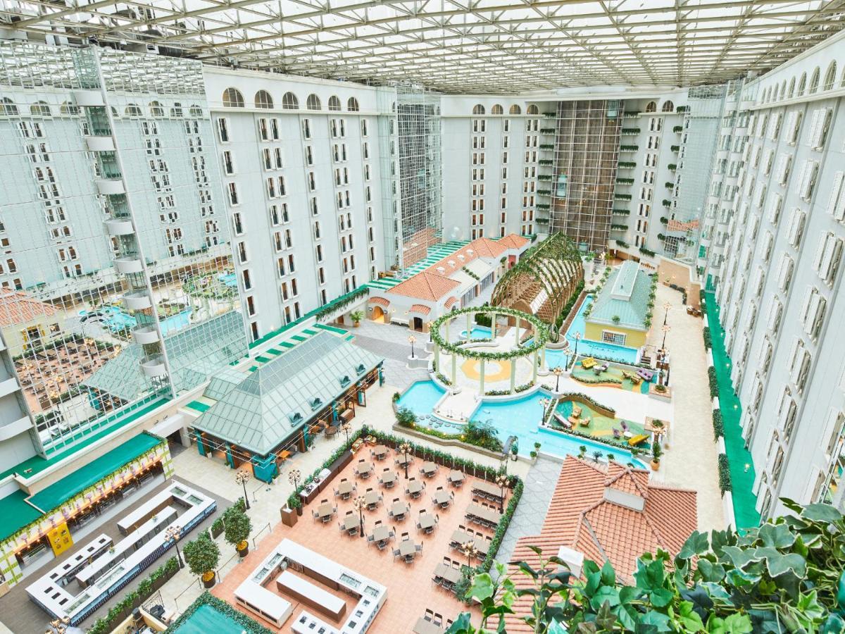 Grand Nikko Tokyo Bay Maihama Hotel Urayasu Eksteriør billede The photo depicts a large indoor area, likely within a resort or hotel, featuring a spacious atrium. The atrium has a glass roof, allowing natural light to flood the space. In the center, there are various swimming pools and a lush, green landscape w