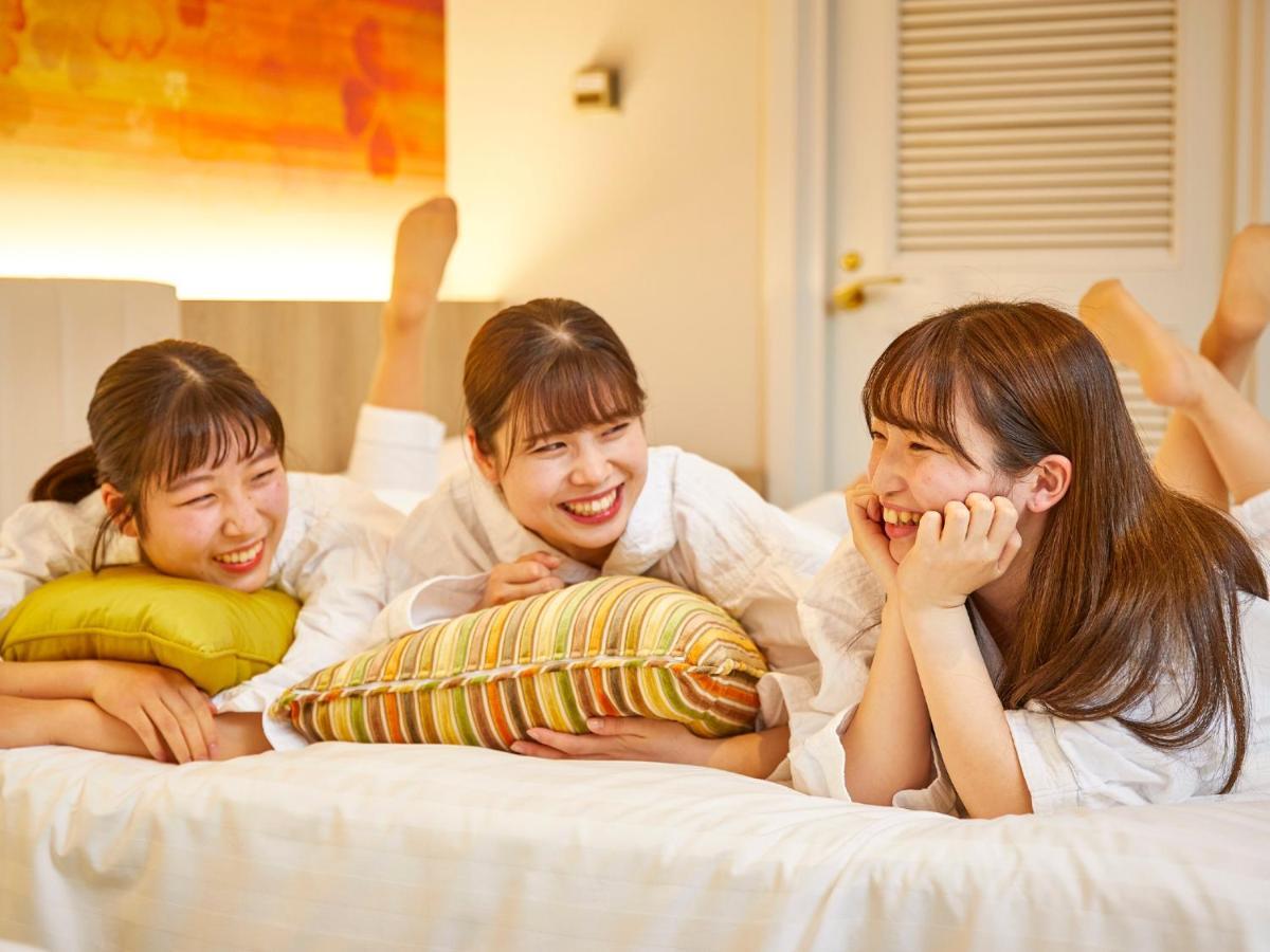 Grand Nikko Tokyo Bay Maihama Hotel Urayasu Eksteriør billede The photo shows three young women lounging together in a cozy indoor setting. They are dressed in white robes and appear to be relaxed and enjoying each other's company. The women are lying on a bed, with two of them resting on their arms and the thi