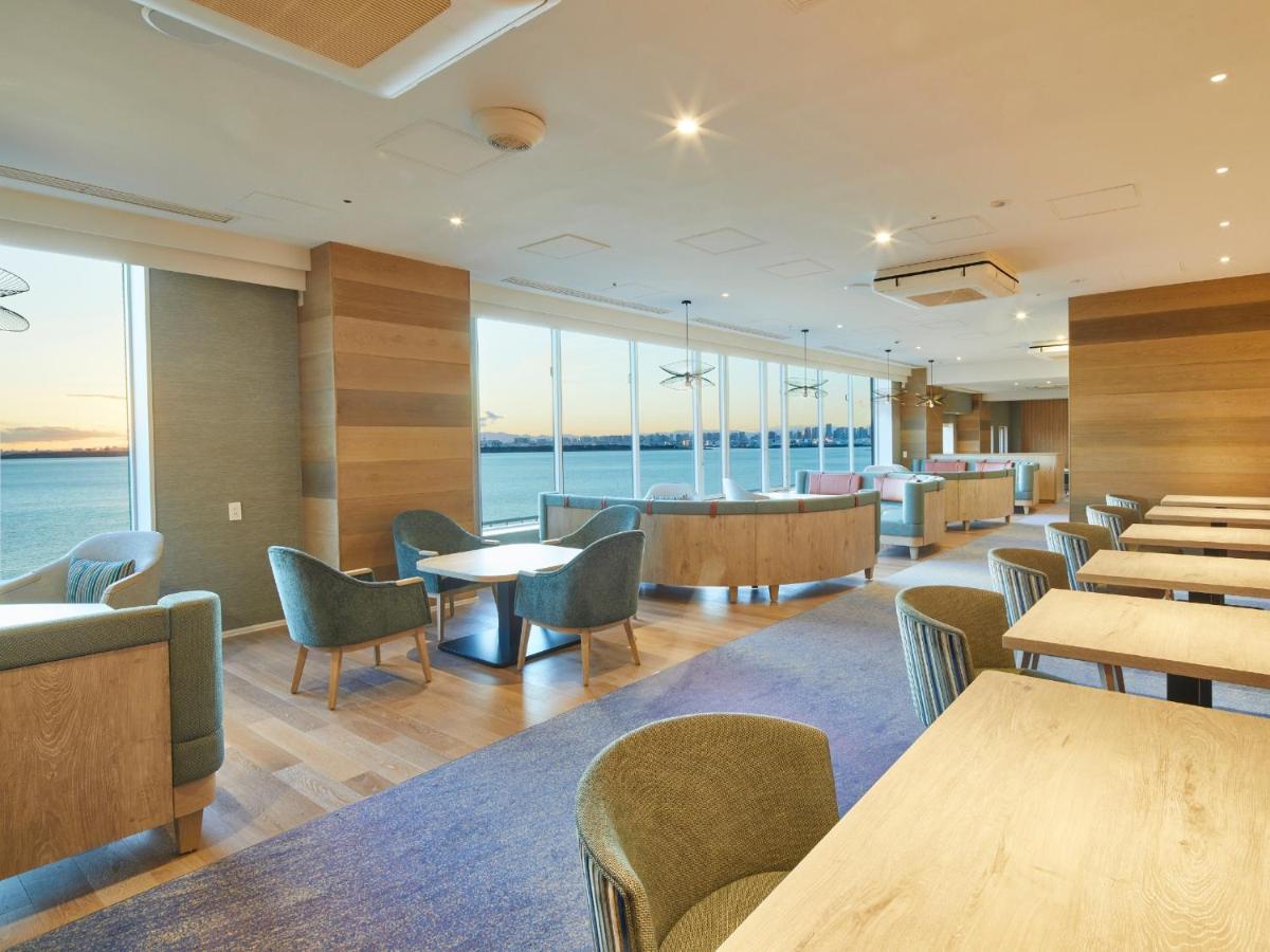 Grand Nikko Tokyo Bay Maihama Hotel Urayasu Eksteriør billede The photo shows a modern interior space, likely a dining or lounge area. It features large windows that offer a view of the water, allowing natural light to fill the room. The decor includes wooden walls and stylish, comfortable furniture, with sever