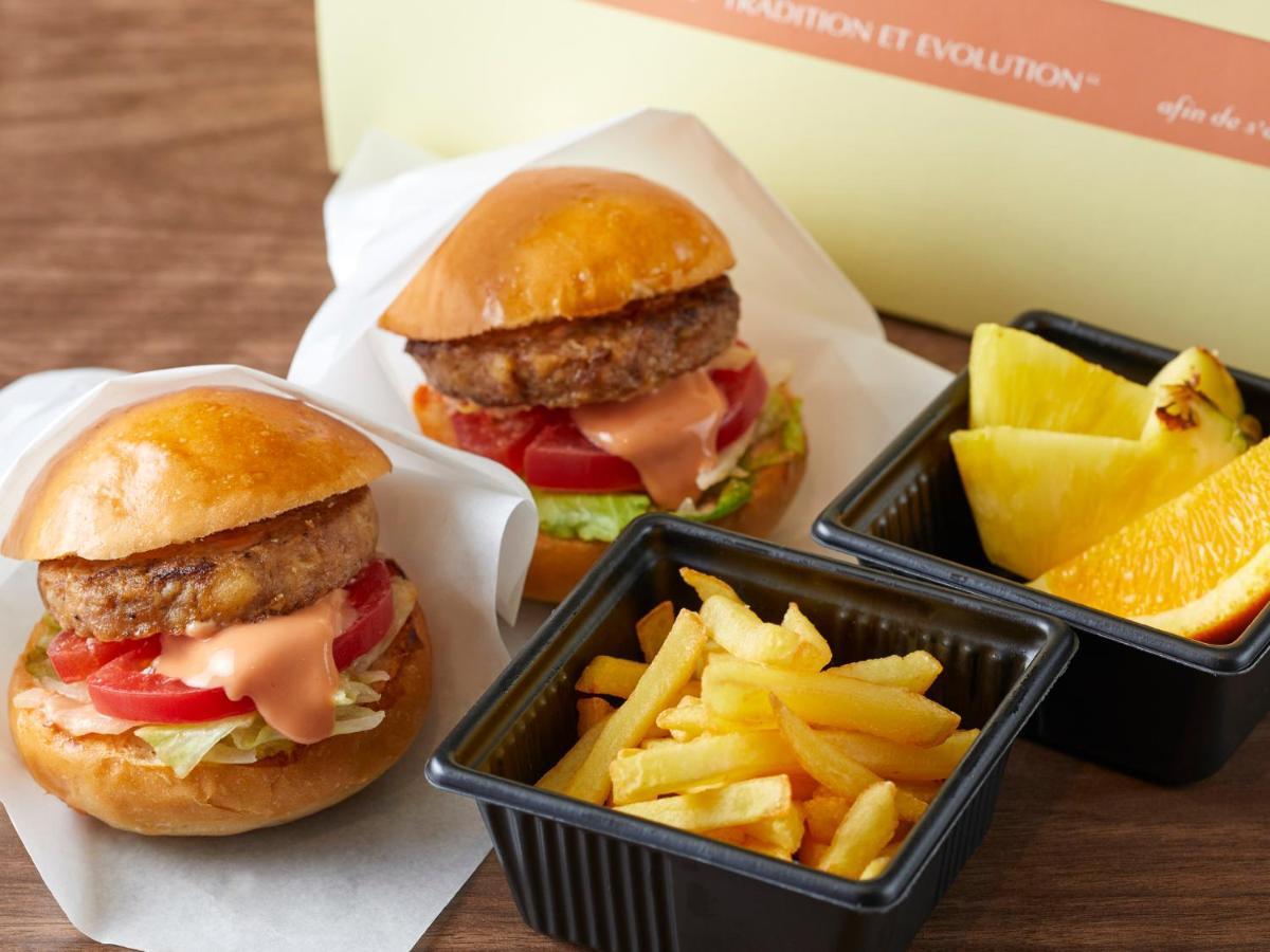 Grand Nikko Tokyo Bay Maihama Hotel Urayasu Eksteriør billede The photo shows two small burgers placed on a white background, each with a golden-brown bun, a fried patty, lettuce, tomato, and a creamy sauce. Alongside the burgers, there are two containers: one holding a serving of french fries and the other con