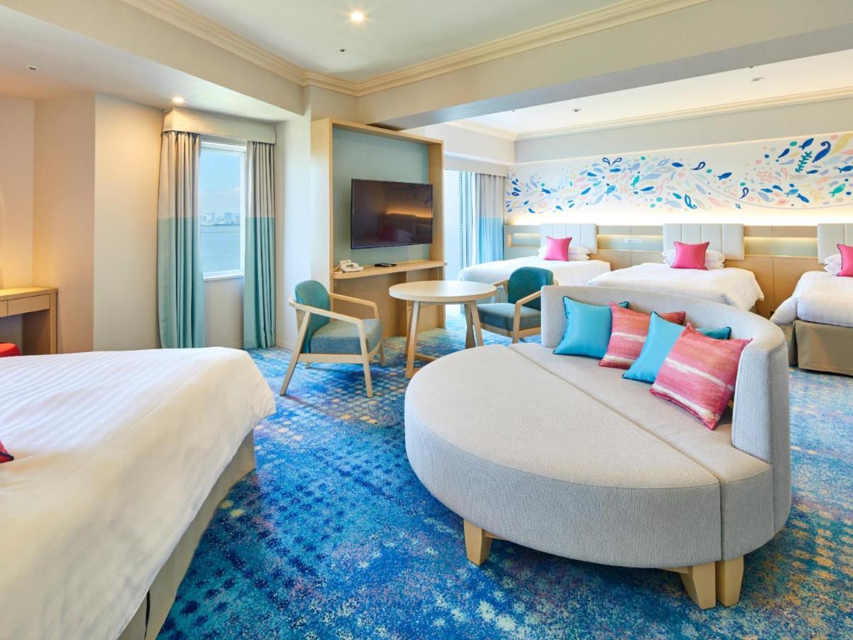 Grand Nikko Tokyo Bay Maihama Hotel Urayasu Eksteriør billede The photo shows a modern hotel room featuring a spacious layout with multiple beds. There is a large, curved sofa with colorful cushions in the center, adding a contemporary touch to the design. The room has large windows allowing natural light to fi