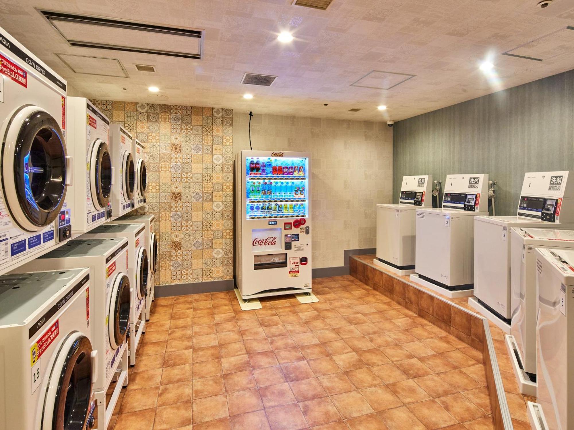 Grand Nikko Tokyo Bay Maihama Hotel Urayasu Eksteriør billede The photo shows a laundry room equipped with several washing machines and dryers. On the left side, there are multiple front-loading washing machines arranged in a row, and on the right side, there are dryers. In the center, there is a vending machin