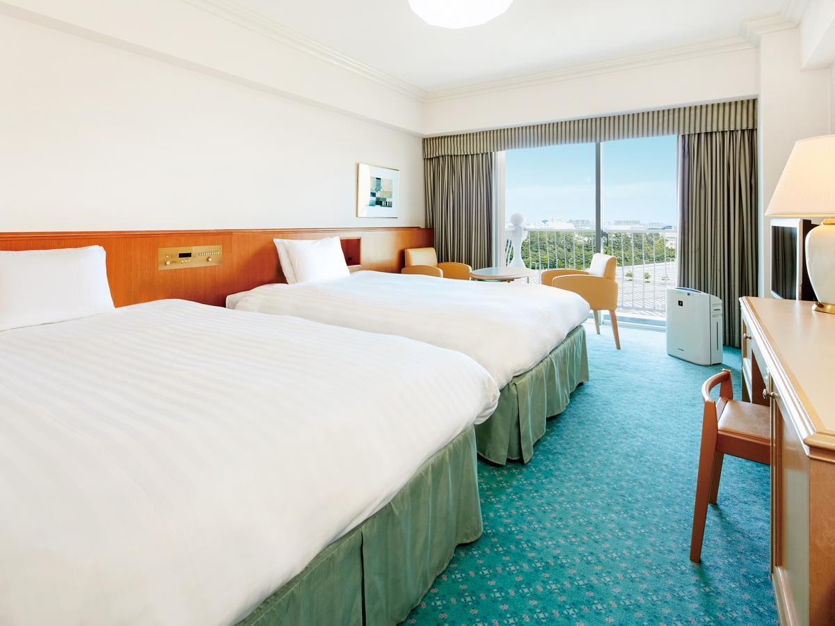 Grand Nikko Tokyo Bay Maihama Hotel Urayasu Eksteriør billede The photo shows a hotel room featuring two twin beds with white bedding. The walls are painted in light colors, and there’s a window that offers a view outside, letting in natural light. A small table and chairs are visible near the window, as well a